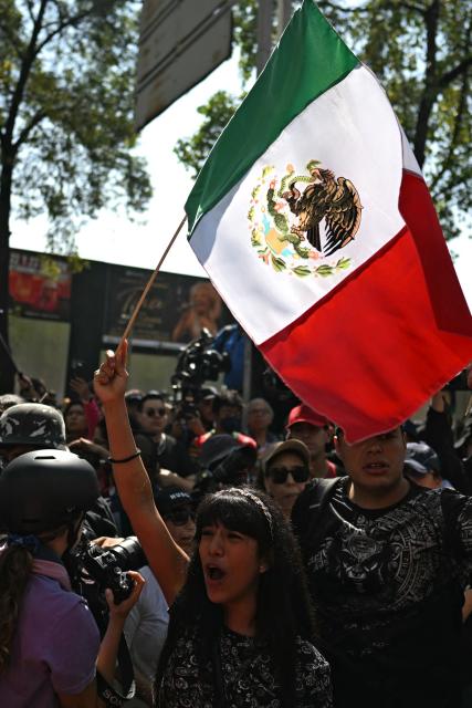 Generation Z youngsters take part in a rally against the government of Mexico's President Claudia Sheinbaum with a Mexican flag, in Mexico City on November 20, 2025. (Photo by CARL DE SOUZA / AFP)