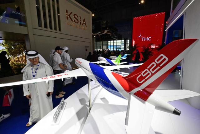 A visitor looks at a model of the Chinese COMAC C929 model displayed at Al-Maktoum International Airport during the Dubai Airshow 2025 in Dubai on November 20, 2025. (Photo by Giuseppe CACACE / AFP)