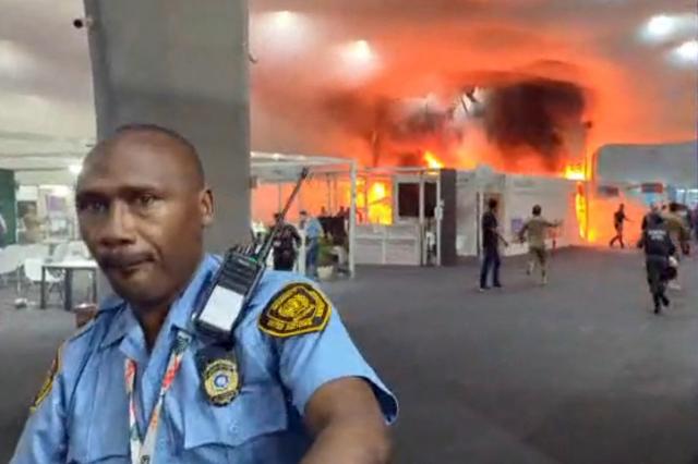 This screen grab taken from AFPTV video footage shows emergency crews battling a fire that broke out at a pavilion inside the venue of the COP30 UN Climate Change Conference in Belem, Para state, Brazil, on November 20, 2025. A fire erupted at a pavilion inside the venue of the UN's climate talks in Brazil on Thursday, prompting panicked delegates to run for the exits, AFP journalists said. Emergency crews rushed to try to put out the blaze as smoke engulfed the corridor. (Photo by AFPTV / AFP)