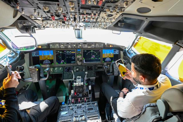 People sit in the cockpit of a FlyDubai 737 Max on display at Al-Maktoum International Airport during the Dubai Airshow 2025 in Dubai on November 20, 2025. (Photo by Giuseppe CACACE / AFP)