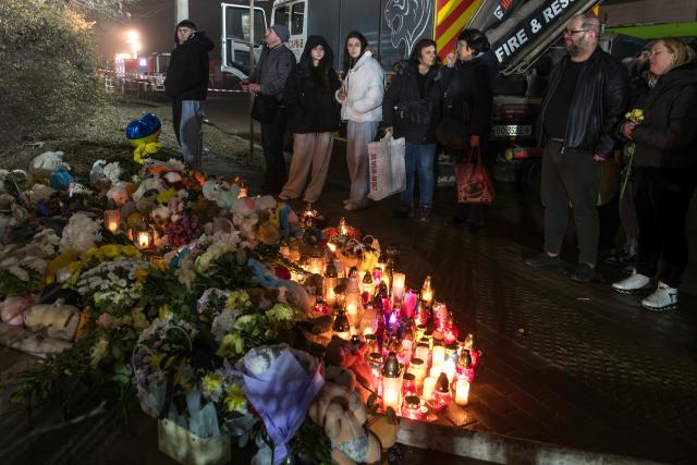 Local residents stand next to a makeshift memorial at the site of a heavily damaged residential building following an air attack in Ternopil on November 20, 2025, amid the Russian invasion of Ukraine. Ukrainian president said on November 20, 2025 that 22 people were still missing in the western city of Ternopil, a day after a Russian strike there killed at least 26 people, including three children. (Photo by Vladyslav Musiienko / AFP)