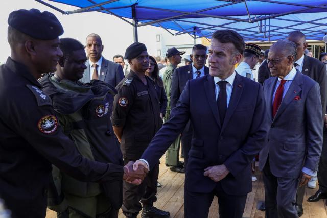 France’s President Emmanuel Macron (C), flanked by Mauritius' Prime Minister Navin Ramgoolam, greets a crew of the Champlain vessel in the harbour near Port Louis on November 21, 2025. (Photo by Ludovic MARIN / AFP)