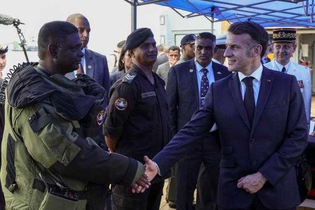 France’s President Emmanuel Macron (R) greets a crew of the Champlain vessel in the harbour near Port Louis on November 21, 2025. (Photo by Ludovic MARIN / AFP)