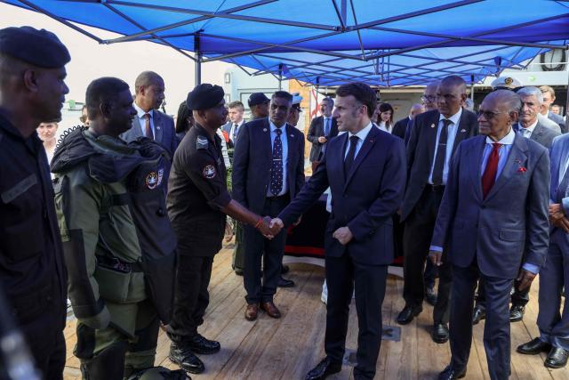 France’s President Emmanuel Macron (C), flanked by Mauritius' Prime Minister Navin Ramgoolam (R), greets a crew of the Champlain vessel in the harbour near Port Louis on November 21, 2025. (Photo by Ludovic MARIN / AFP)