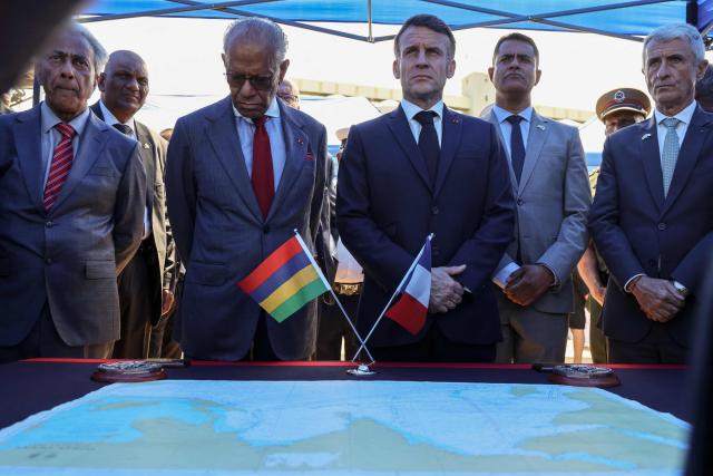 France’s President Emmanuel Macron (CR) and Mauritius' Prime Minister Navin Ramgoolam (CL) listen to the crew members of the Champlain vessel in the harbour near Port Louis on November 21, 2025. (Photo by Ludovic MARIN / AFP)