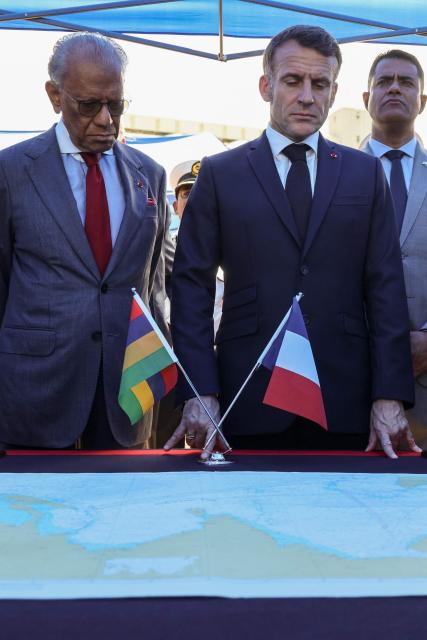 France’s President Emmanuel Macron (C) and Mauritius' Prime Minister Navin Ramgoolam (L) listen to the crew members of the Champlain vessel in the harbour near Port Louis on November 21, 2025. (Photo by Ludovic MARIN / AFP)