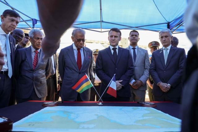 France’s President Emmanuel Macron (CR) and Mauritius' Prime Minister Navin Ramgoolam (CL) listen to the crew members of the Champlain vessel in the harbour near Port Louis on November 21, 2025. (Photo by Ludovic MARIN / AFP)