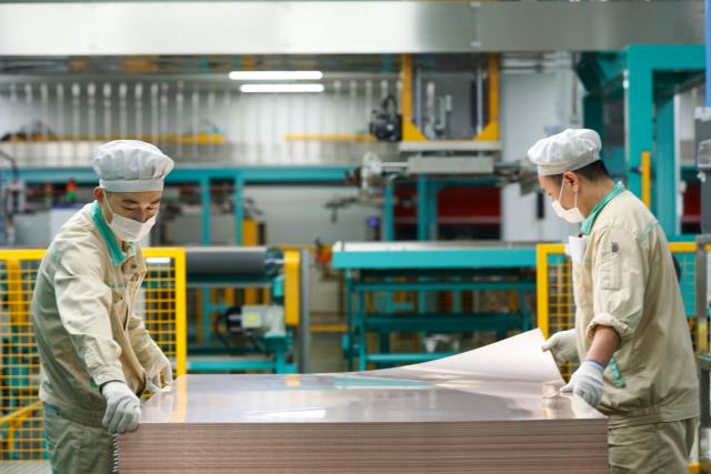 Men work on the production of electronic circuit base materials for high-performance computing, AI servers, 5G communications, and aerospace applications at Jiangxi Shengyi Technology in Jiujiang, central China's Jiangxi province on November 20, 2025. (Photo by AFP) / China OUT