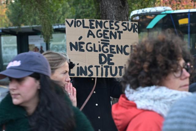 A demonstrator holds a placard reading 'Violence against a civil servant, institutional negligence' during a rally in support of the headmaster of Les Cloteaux nursery school who was threatened by a parent who did not want his daughter to have a male teacher, in Rennes, western France, on November 21, 2025. The headmaster and teacher of a state nursery school in Rennes has been the victim of threatening remarks from a family who refuse to allow their daughter to be taught by a man, which has led to a complaint being lodged, according to corroborating sources on November 20, 2025. (Photo by Damien MEYER / AFP)
