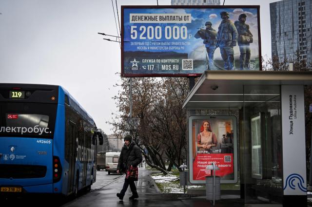 A man walks past a billboard promoting contract army service and reading "5 200 000 rubles for the first year of the contract" (about USD 66 000) in western Moscow on November 21, 2025. Ukraine woke up Friday to a US peace proposal that would force it to essentially capitulate to Russia after almost four years of war -- requiring Kyiv to give up land, cut its army and hold elections. US President Donald Trump backs the 28-point surprise plan that would also see Kyiv pledge never to join NATO. (Photo by Alexander NEMENOV / AFP)