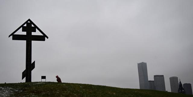 A woman gives a cross sign near the Museum of the Great Patriotic War (also known as the Victory Museum ) at Poklonnaya Hill in western Moscow on November 21, 2025. Ukraine woke up Friday to a US peace proposal that would force it to essentially capitulate to Russia after almost four years of war -- requiring Kyiv to give up land, cut its army and hold elections. US President Donald Trump backs the 28-point surprise plan that would also see Kyiv pledge never to join NATO. (Photo by Alexander NEMENOV / AFP)