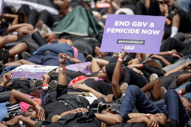Protesters hold placards as they lie on the ground during the Women's Nationwide Shutdown at Constitution Hill in Johannesburg on November 21, 2025, ahead of the G20 leaders' Summit. Women for Change calls on the community across South Africa to refrain from all paid and unpaid work in workplaces, universities, and homes, and to spend no money for the entire day to demonstrate the economic and social impact of their absence, and demand that gender-based violence and femicide be declared a national disaster. (Photo by GIANLUIGI GUERCIA / AFP)