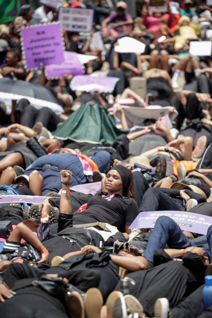 Protesters hold placards as they lie on the ground during the Women's Nationwide Shutdown at Constitution Hill in Johannesburg on November 21, 2025, ahead of the G20 leaders' Summit. Women for Change calls on the community across South Africa to refrain from all paid and unpaid work in workplaces, universities, and homes, and to spend no money for the entire day to demonstrate the economic and social impact of their absence, and demand that gender-based violence and femicide be declared a national disaster. (Photo by GIANLUIGI GUERCIA / AFP)