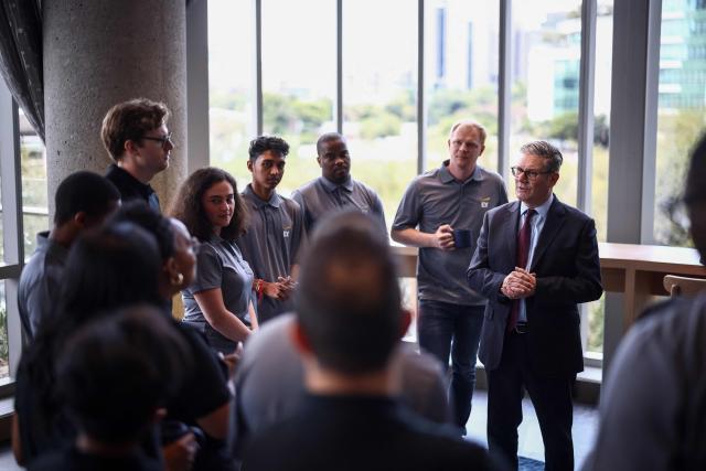 Britain's Prime Minister Keir Starmer (R) speaks to apprentices during a reception at EY headquarters in Johannesburg, on November 21, 2025 ahead of the G20 leaders' Summit. (Photo by HENRY NICHOLLS / POOL / AFP)