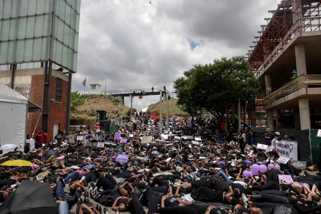 Protesters hold placards as they lie on the ground during the Women's Nationwide Shutdown at Constitution Hill in Johannesburg on November 21, 2025, ahead of the G20 leaders' Summit. Women for Change calls on the community across South Africa to refrain from all paid and unpaid work in workplaces, universities, and homes, and to spend no money for the entire day to demonstrate the economic and social impact of their absence, and demand that gender-based violence and femicide be declared a national disaster. (Photo by GIANLUIGI GUERCIA / AFP)