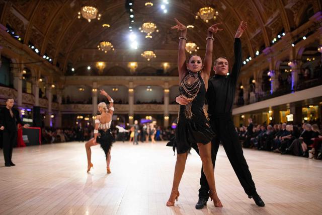 Latin dancing couple Rhys Palmer (R) and Millie Rose Cross (2nd R) compete in the 'Amateur Under 21 years Latin Championship' of the 50th British National Dance Championships, in the Empress Ballroom of Blackpool's Winter Gardens, in Blackpool, north-west England, on November 20, 2025. The annual, four-day British National Dance Championship features over 2000 entries and showcases 60 hours of competitive dancing, with 23 championship titles in Ballroom and Latin dance disciplines. (Photo by Oli SCARFF / AFP)