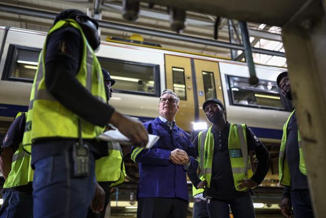Britain's Prime Minister Keir Starmer (C) speaks to employees as he visits Johannesburg's Gautrain depot workshop in Midrand, on November 21, 2025. The Gautrain carriages are made in Alstom’s factory in Derby, UK. (Photo by HENRY NICHOLLS / POOL / AFP)