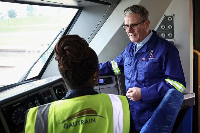 Britain's Prime Minister Keir Starmer (R) speaks to an employee as he visits Johannesburg's Gautrain depot workshop in Midrand, on November 21, 2025. The Gautrain carriages are made in Alstom’s factory in Derby, UK. (Photo by HENRY NICHOLLS / POOL / AFP)
