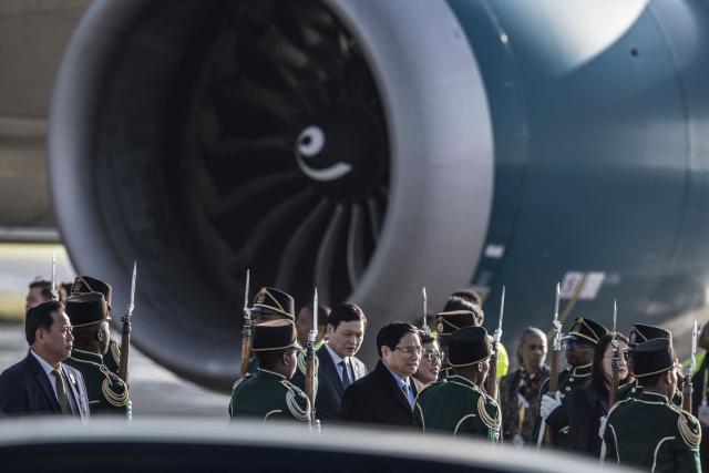 Vietnam Prime Minister Pham Minh Chinh (C) walks through a South African National Defense Forces (SANDF) honor guard  upon his arrival at the OR Tambo International airport in Ekurhuleni on November 21, 2025 ahead of the G20 leader's Summit. (Photo by MARCO LONGARI / POOL / AFP)