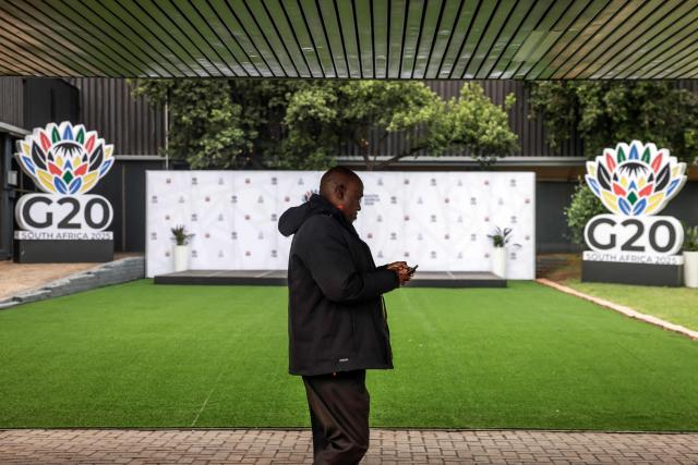 A delegate walks past G20 logos displayed at the Nasrec Expo Centre in Johannesburg on November 21, 2025, ahead of the G20 Leaders' Summit. (Photo by GIANLUIGI GUERCIA / AFP)