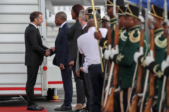 France’s President Emmanuel Macron (L) is welcomed by South African Minister of the Department of Cooperative Governance and Traditional Affairs (COGTA) Velenkosini Hlabisa (2nd L) upon Macron's arrival at the OR Tambo International airport in Ekurhuleni on November 21, 2025 ahead of the G20 leader's Summit. (Photo by Ludovic MARIN / AFP)
