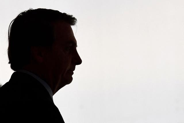 (FILES) The silhouette of Brazilian President Jair Bolsonaro is seen as he arrives for the Armed Forces General Officers promotion ceremony at Planalto Palace in Brasilia on December 9, 2019. Lawyers for former Brazilian president Jair Bolsonaro on November 21, 2025, requested he be allowed to serve a 27-year prison sentence for coup plotting under house arrest, citing ill health. (Photo by EVARISTO SA / AFP)