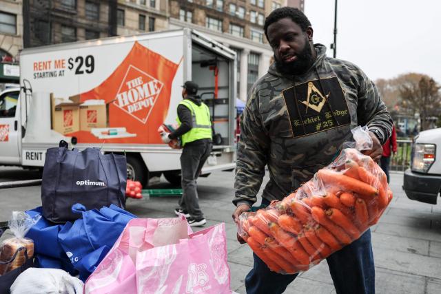 A volunteer carries a bag of carrots during a Thanksgiving food distribution event outside of Brooklyn Borough Hall on November 21, 2025 in New York City. Fresh produce, non-perishables and other food items were handed out to 125 Brooklyn houses of worship, community kitchens and other community-based organizations addressing food insecurity and homelessness. (Photo by ANGELA WEISS / AFP)