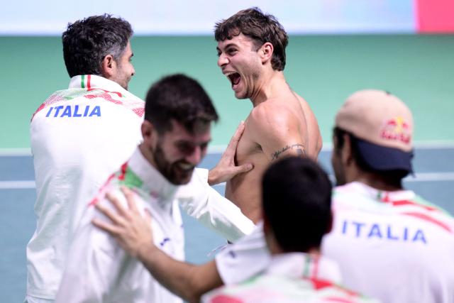 Italy's Flavio Cobolli (R) celebrates with team mates after winning his 2025 Davis Cup semi-final single tennis match between Italy and Belgium at the Super Tennis Arena in Bologna, northen Italy, on November 21, 2025. (Photo by Tiziana FABI / AFP)