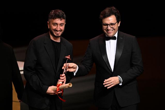 Kurdish-Turkish filmmaker Seyhmus Altun (L) reacts after receiving the Bronze Pyramid Award for his film "As We Breathe" during the closing ceremony of the 46th Cairo International Film Festival in Cairo on November 21, 2025. (Photo by Khaled DESOUKI / AFP)