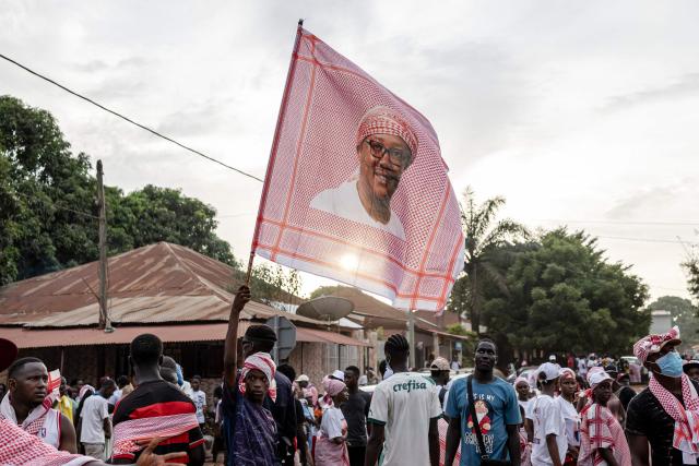 A supporter of Guinea-Bissau's President and presidential candidate Umaro Sissoco Embalo waves a red keffiyeh bearing his image during his final campaign rally ahead of general elections, in Bissau, on November 21, 2025. Guinea-Bissau votes in general elections on November 23, 2025. (Photo by PATRICK MEINHARDT / AFP)