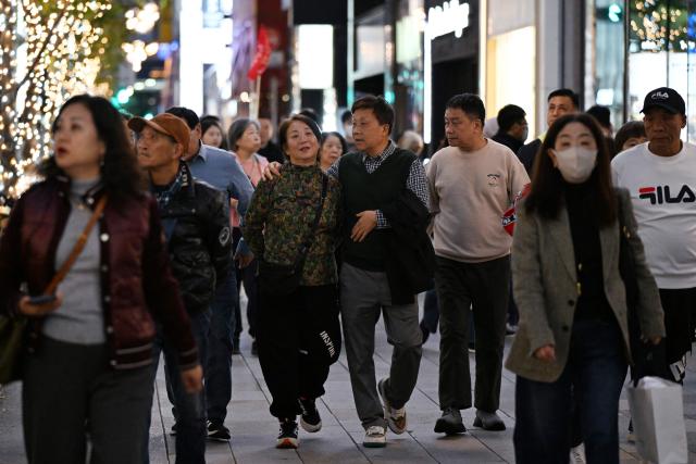 (FILES) A Chinese tour group walks in the Ginza shopping district in Tokyo on November 17, 2025. Taiwan lifted all restrictions on Japanese food imports on November 22, in another show of support for Tokyo after reports that China will stop purchases over a row with the new prime minister. (Photo by GREG BAKER / AFP)