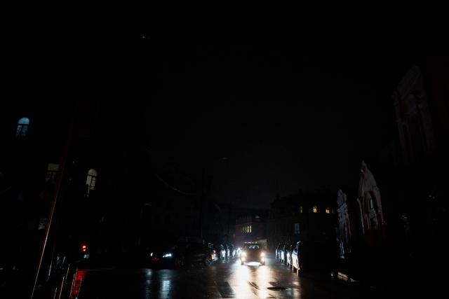 Commuters drive their vehicles on a non-illuminated street during blackout hours in Kyiv on November 21, 2025, following Russian missile and drone attacks on Ukrainian energy infrastructure amid the Russian invasion of Ukraine. (Photo by Tetiana DZHAFAROVA / AFP)