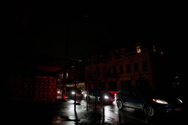 Commuters drive their vehicles on a non-illuminated street during blackout hours in Kyiv on November 21, 2025, following Russian missile and drone attacks on Ukrainian energy infrastructure amid the Russian invasion of Ukraine. (Photo by Tetiana DZHAFAROVA / AFP)