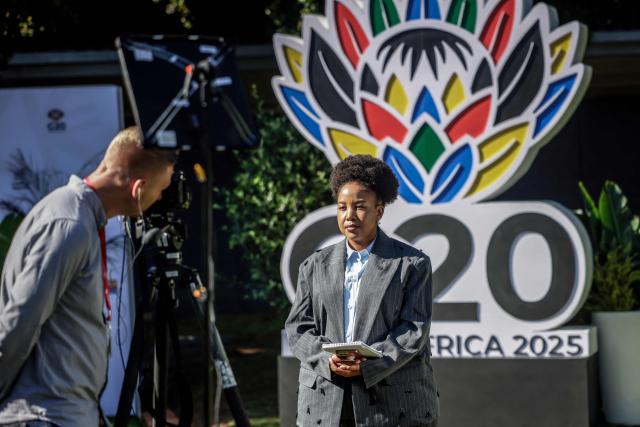 A journalist presents ahead of the opening of the G20 Leaders' Summit at the Nasrec Expo Centre in Johannesburg on November 22, 2025. (Photo by GIANLUIGI GUERCIA / AFP)