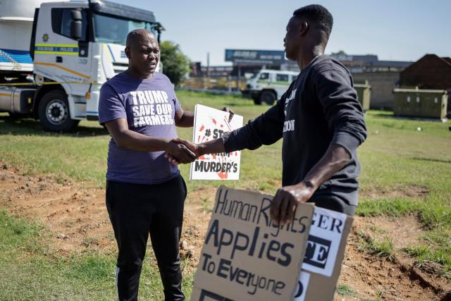 A Farmer Lives Matter protester (L) shakes hands with a pro-Palestinian protester (R) as they stand next to a road near the Nasrec Expo Centre in Johannesburg on November 22, 2025 ahead of the opening of the G20 Leader's Summit. (Photo by EMMANUEL CROSET / AFP)