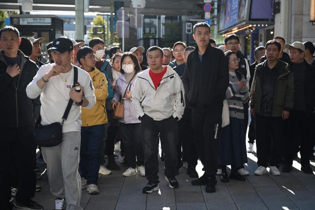 Tourists from China walk on a street in the Ginza shopping district in Tokyo on November 22, 2025. A souring of Beijing-Tokyo relations this month, following remarks by Japanese Prime Minister Sanae Takaichi about Taiwan, has fuelled concerns about the impact on the ritzy boutiques, noodle joints and hotels where holidaymakers spend their cash. (Photo by GREG BAKER / AFP) / To go with AFP story Japan-China-diplomacy-tourism, REPORTAGE by Mathias Cena, Kyoko Hasegawa, and Jing Xuan Teng