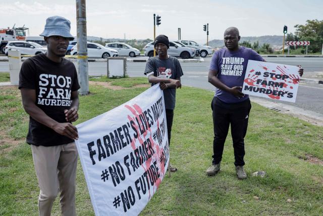 Farmer Lives Matter protesters hold signs next to a road near the Nasrec Expo Centre in Johannesburg on November 22, 2025 ahead of the opening of the G20 Leader's Summit. (Photo by EMMANUEL CROSET / AFP)