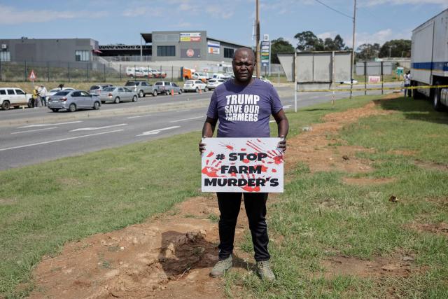 A Farmer Lives Matter protester holds a sign next to a road near the Nasrec Expo Centre in Johannesburg on November 22, 2025 ahead of the opening of the G20 Leader's Summit. (Photo by EMMANUEL CROSET / AFP)