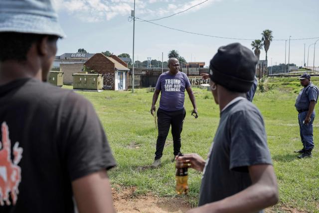 A Farmer Lives Matter protester (C) stands in a fields next to a road near the Nasrec Expo Centre in Johannesburg on November 22, 2025 ahead of the opening of the G20 Leader's Summit. (Photo by EMMANUEL CROSET / AFP)