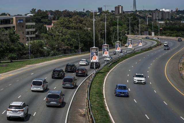 A convoy of vehicles carrying delegates drives past banners bearing the photograph of India's Prime Minister Narendra Modi on a major freeway heading toward the Nasrec Expo Centre in Johannesburg on November 22, 2025, ahead of the opening of the G20 Leader's Summit. (Photo by Zinyange Auntony / AFP)