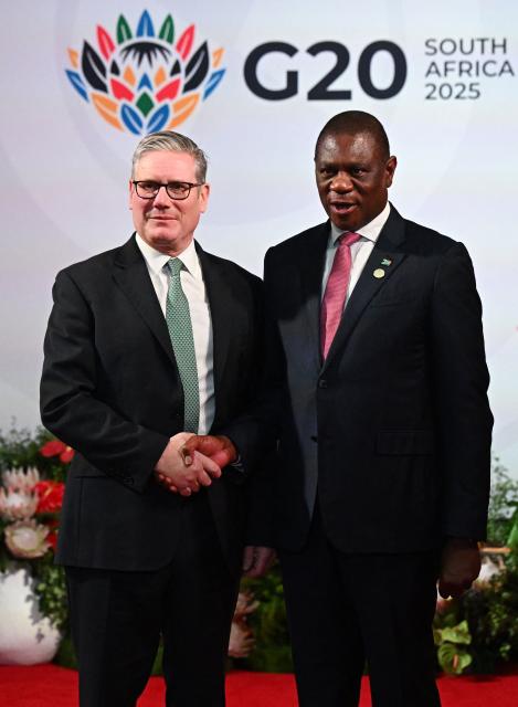 South Africa's Deputy President Paul Mashatile (R) welcomes Britain's Prime Minister Keir Starmer (L)  upon his arrival for the opening of the G20 Leaders' Summit at the Nasrec Expo Centre in Johannesburg on November 22, 2025. (Photo by Leon Neal / POOL / AFP)