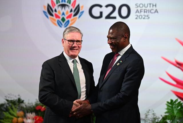 South Africa's Deputy President Paul Mashatile (R) welcomes Britain's Prime Minister Keir Starmer (L)  upon his arrival for the opening of the G20 Leaders' Summit at the Nasrec Expo Centre in Johannesburg on November 22, 2025. (Photo by Leon Neal / POOL / AFP)