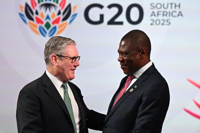 South Africa's Deputy President Paul Mashatile (R) welcomes Britain's Prime Minister Keir Starmer (L)  upon his arrival for the opening of the G20 Leaders' Summit at the Nasrec Expo Centre in Johannesburg on November 22, 2025. (Photo by Leon Neal / POOL / AFP)