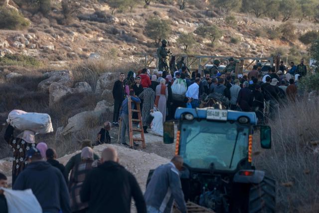 Israeli soldiers stop Palestinian farmers from Salem village at a checkpoint before entering through a close gate onto their land to pick olives, east of Nablus in the occupied West Bank, on November 22, 2025. (Photo by Jaafar ASHTIYEH / AFP)
