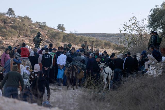 Israeli soldiers stop Palestinian farmers from Salem village at a checkpoint before entering through a close gate onto their land to pick olives, east of Nablus in the occupied West Bank, on November 22, 2025. (Photo by Jaafar ASHTIYEH / AFP)