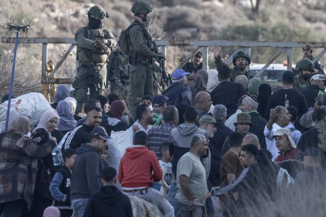 TOPSHOT - Israeli soldiers stop Palestinian farmers from Salem village at a checkpoint before entering through a closed gate onto their land to pick olives, east of Nablus in the occupied West Bank, on November 22, 2025. (Photo by Jaafar ASHTIYEH / AFP)