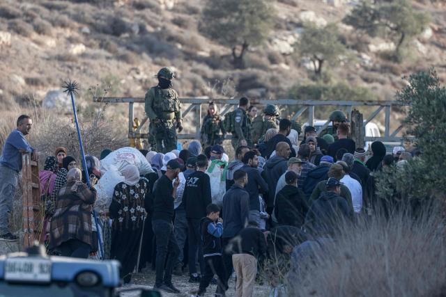Israeli soldiers stop Palestinian farmers from Salem village at a checkpoint before entering through a close gate onto their land to pick olives, east of Nablus in the occupied West Bank, on November 22, 2025. (Photo by Jaafar ASHTIYEH / AFP)