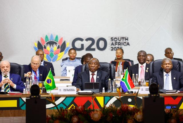 South Africa's President Cyril Ramaphosa (C) speaks alongside Brazil's President Luiz Inacio Lula da Silva (L) and Chairperson of the African Union Joao Lourenco (R) during the G20 Leaders' Summit plenary session at the Nasrec Expo Centre, in Johannesburg on November 22, 2025. (Photo by Thomas Mukoya / POOL / AFP)