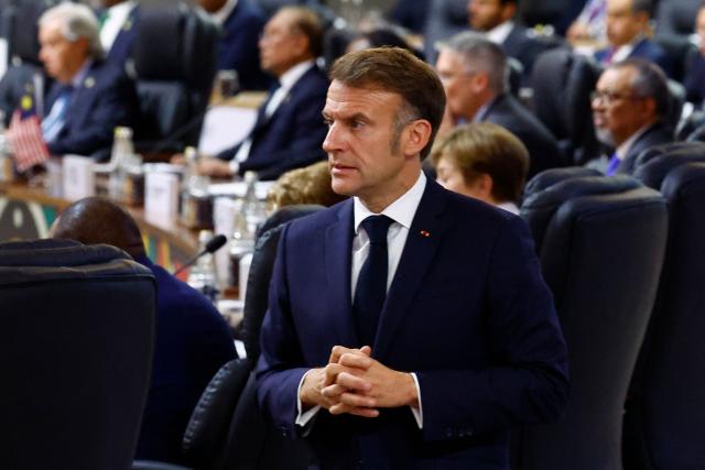 France's President Emmanuel Macron reacts as he arrives to attend the G20 Leaders' Summit plenary session at the Nasrec Expo Centre, in Johannesburg on November 22, 2025. (Photo by Thomas Mukoya / POOL / AFP)