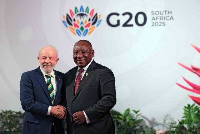 South Africa's President Cyril Ramaphosa (R) shakes hands with Brazil's President Luiz Inacio Lula da Silva (R) as he arrives for the opening of the G20 Leaders' Summit at the Nasrec Expo Centre in Johannesburg on November 22, 2025. (Photo by Halden KROG / POOL / AFP)